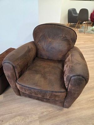 un fauteuil et un pouf en cuir marron dans un salon
