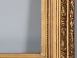 a close up of a gold framed mirror on a wooden table