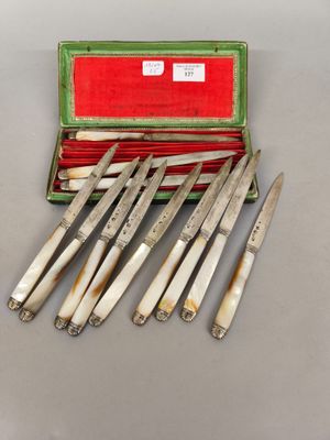 six couteaux dans un étui, posé sur une table avec une boîte rouge à côté
