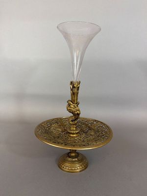 a gold plate with a glass vase on top of it