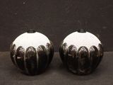 two black and white vases sitting on a black surface