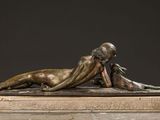 bronze sculpture of a woman laying on her stomach on a marble base
