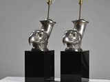 pair of silver vases on black stands on a white surface