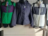 several jackets and bags are hanging on a rack in a room