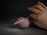 une main tenant un objet rose posé sur une table