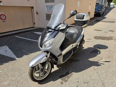 une moto argentée garée sur un parking à côté d'un immeuble