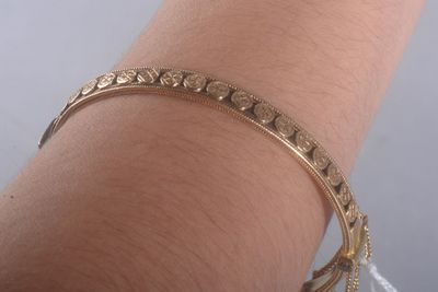 Quelqu'un porte un bracelet en or orné d'un motif.