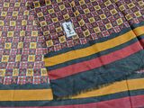 a close up of a red, yellow, and black scarf on a bed