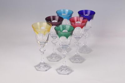 several different colored wine glasses are lined up on a white surface