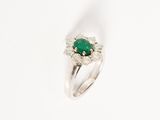 a close up of a ring with a green stone surrounded by diamonds