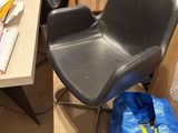 a black chair sitting in front of a desk with a blue bag on it