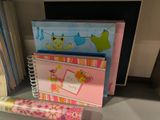 a stack of baby shower books and a roll of wrapping paper on a shelf