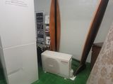an image of a room with a refrigerator and a surfboard