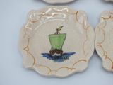 three plates with a boat painted on them on a table
