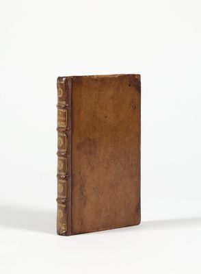 un vieux livre à la couverture brune posé sur une surface blanche