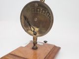 une horloge posée sur un socle en bois, sur une surface blanche