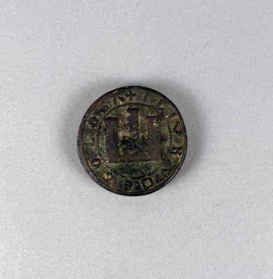 une vieille pièce de monnaie sur laquelle figure une croix, posée sur une surface blanche