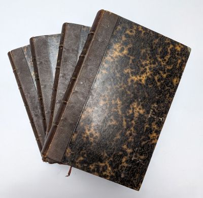 trois vieux livres sont empilés sur une surface blanche