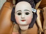 a doll with a bald head sitting on a chair