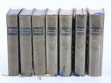 six vieux livres sont alignés sur une surface blanche