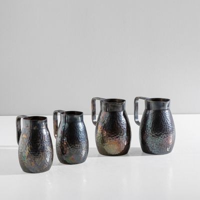 trois pichets en argent posés les uns à côté des autres sur une table blanche