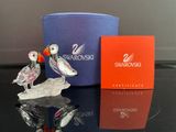 une figurine en verre représentant un oiseau et une boîte posées sur une table