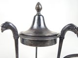 a silver tea pot on a stand on a white background