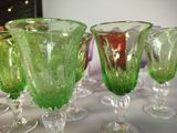 several green glass goblets sitting on top of a white table