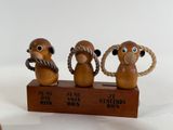three wooden monkey figurines sitting on a wooden stand