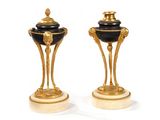 pair of black and gold vases on marble bases on a white surface