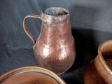 a brown pitcher sitting on a table next to other brown pots