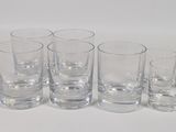 six glasses are lined up in a row on a white surface