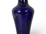 un vase bleu bordé d'or posé sur une surface blanche