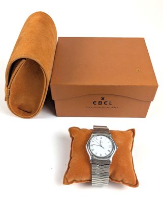 une photo montrant une montre posée sur une boîte, à côté d'une paire de chaussures