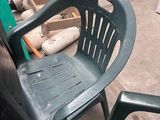 a green plastic chair sitting in the middle of a parking lot