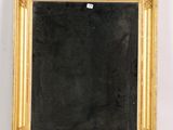 un miroir ancien à cadre doré accroché à un mur blanc, sur fond noir