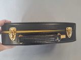 a person holding a black suitcase with gold handles