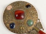 a gold plate with a red handle and some stones on it