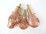 three antique copper wine bottles on a white surface