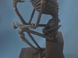 statue of a skeleton sitting on a box with a skull on top of it