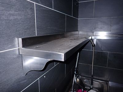 une photo d'une salle de bains avec un lavabo et une étagère en métal
