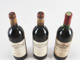 three bottles of wine are lined up on a white surface