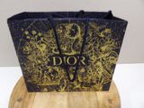 christian dior black and gold gift bag on a wooden stand