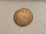 a close up of a gold coin with a cross on it