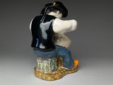 a figurine of a man sitting on top of a tree stump