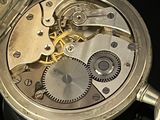 a silver pocket watch that is open on a black surface