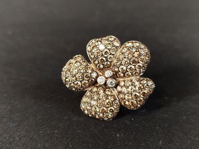 un gros plan d'une broche en forme de fleur dorée posée sur une surface noire