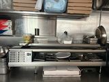 un plan de travail en acier inoxydable sur lequel sont posés des casseroles et des poêles, dans une cuisine professionnelle