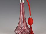 une bouteille en verre rouge avec une poignée rouge et un pompon rouge