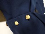 the back of a blue jacket with gold buttons on a white surface